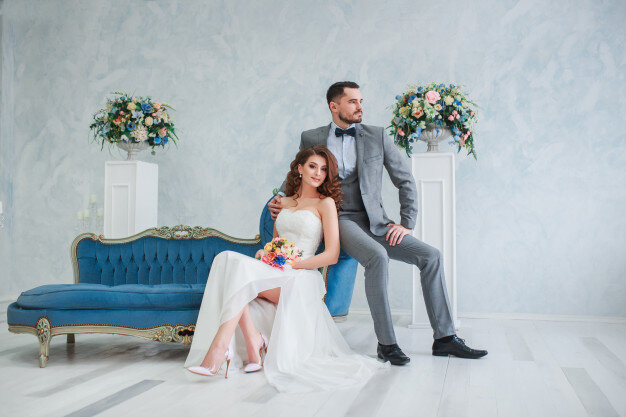 bride-beautiful-dress-groom-gray-suit-sitting-sofa-indoors-trendy-wedding-style_153585-127