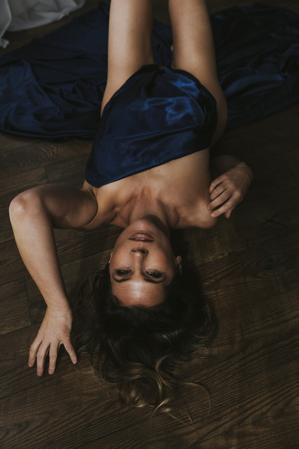 woman laying on the floor with a blue satin sheet