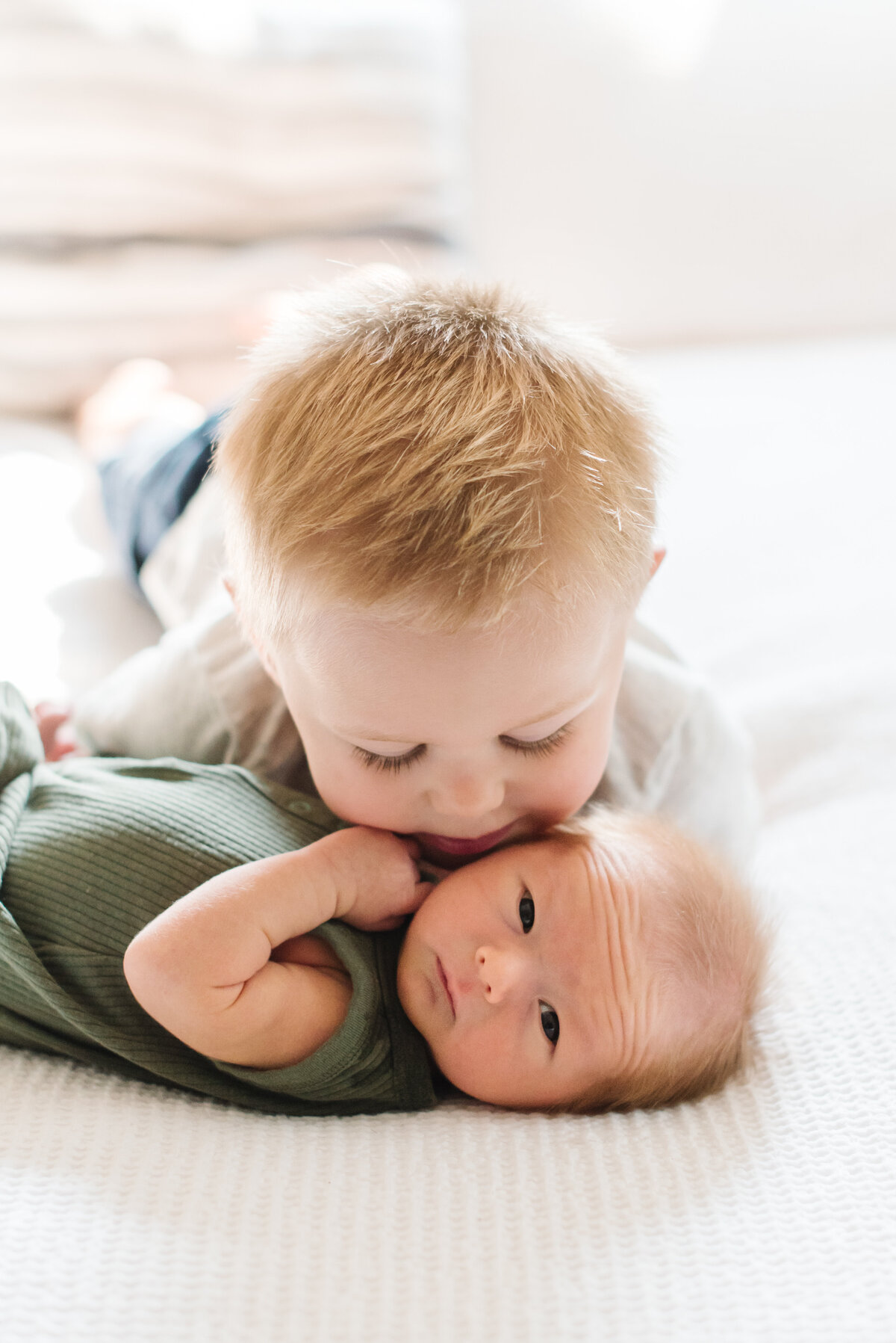 Big brother giving baby sibling a kiss for the camera