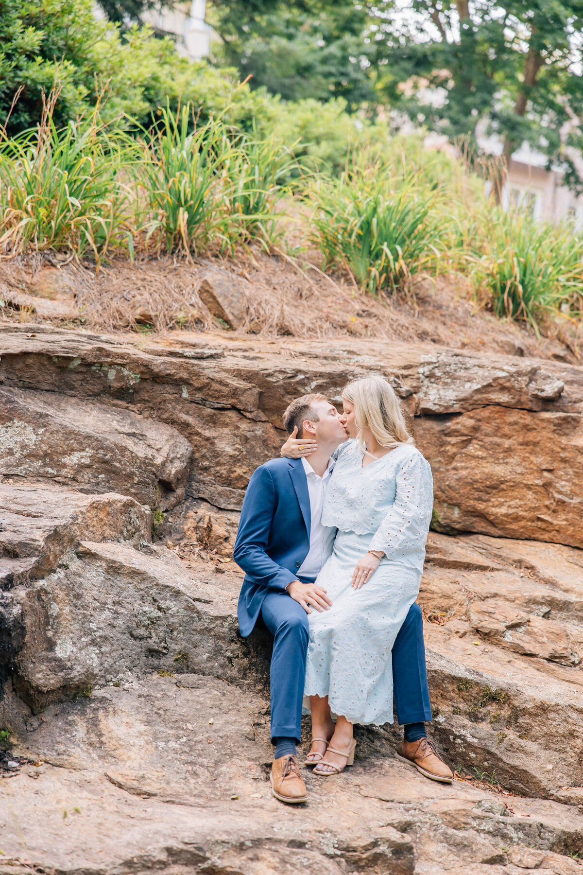 girl sitting on guys lap kissing him on the rocks in greenville, south carolina