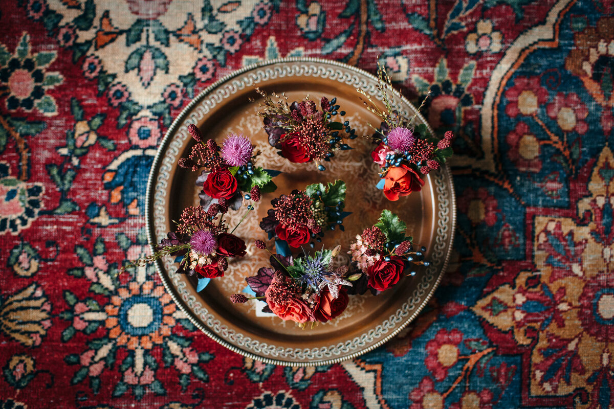 Red floral buttonholes on gold tray on antique rug
