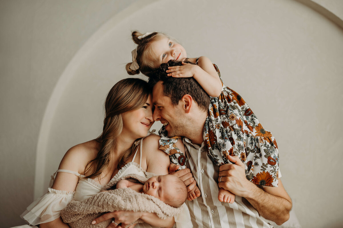 toddler lays on her dads head while sitting on his shoulders during a family photo session in colorado
