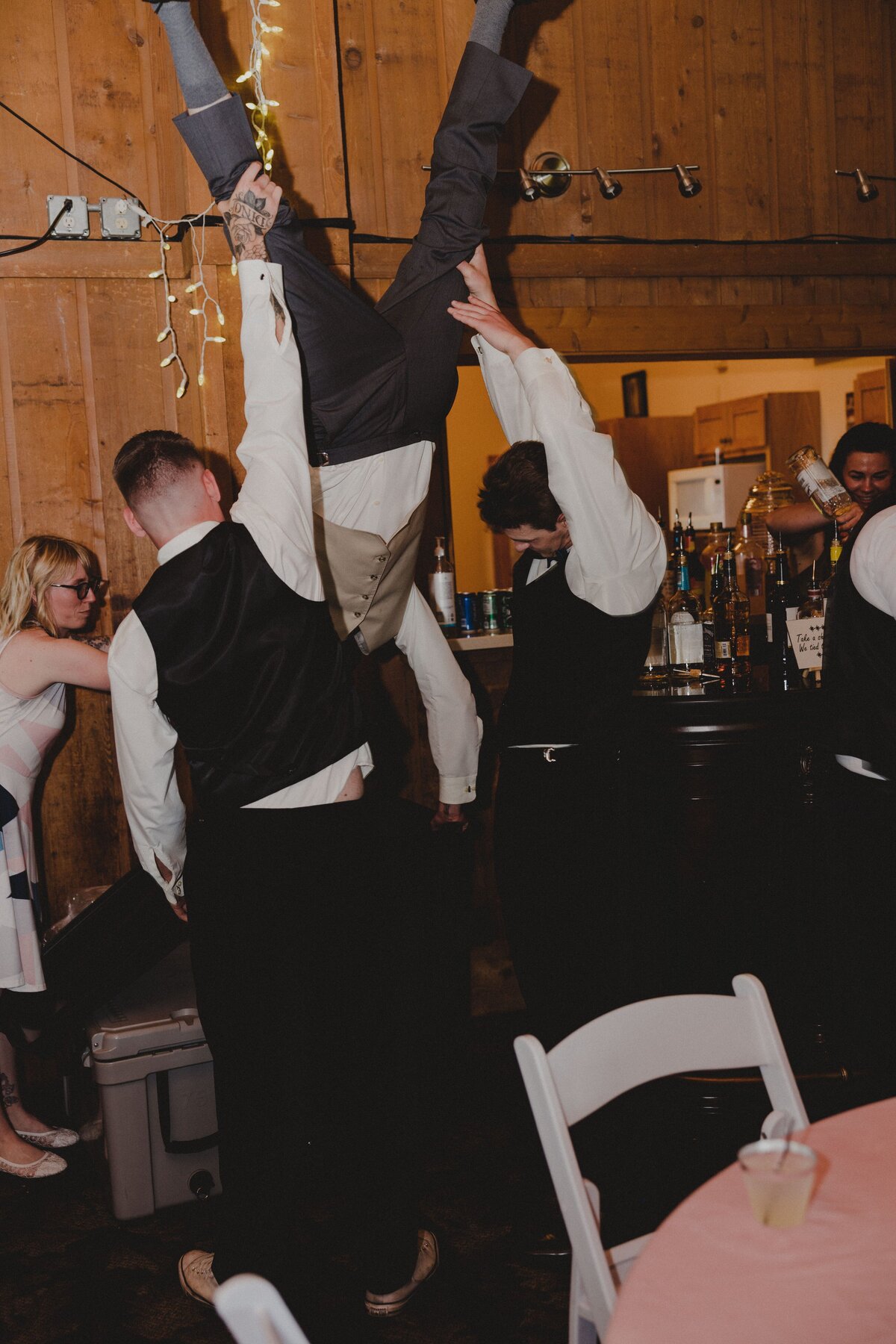 A groom does a keg stand during his wedding reception