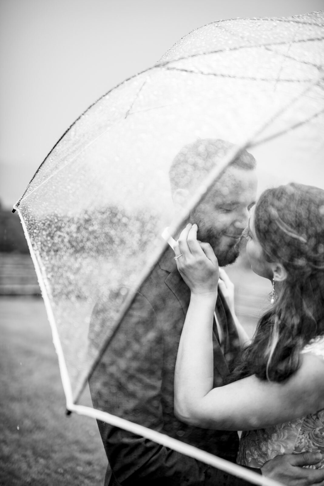 black and white photo of couple kissing under umbrella at rainy mountain top inn resort wedding chittenden vermont