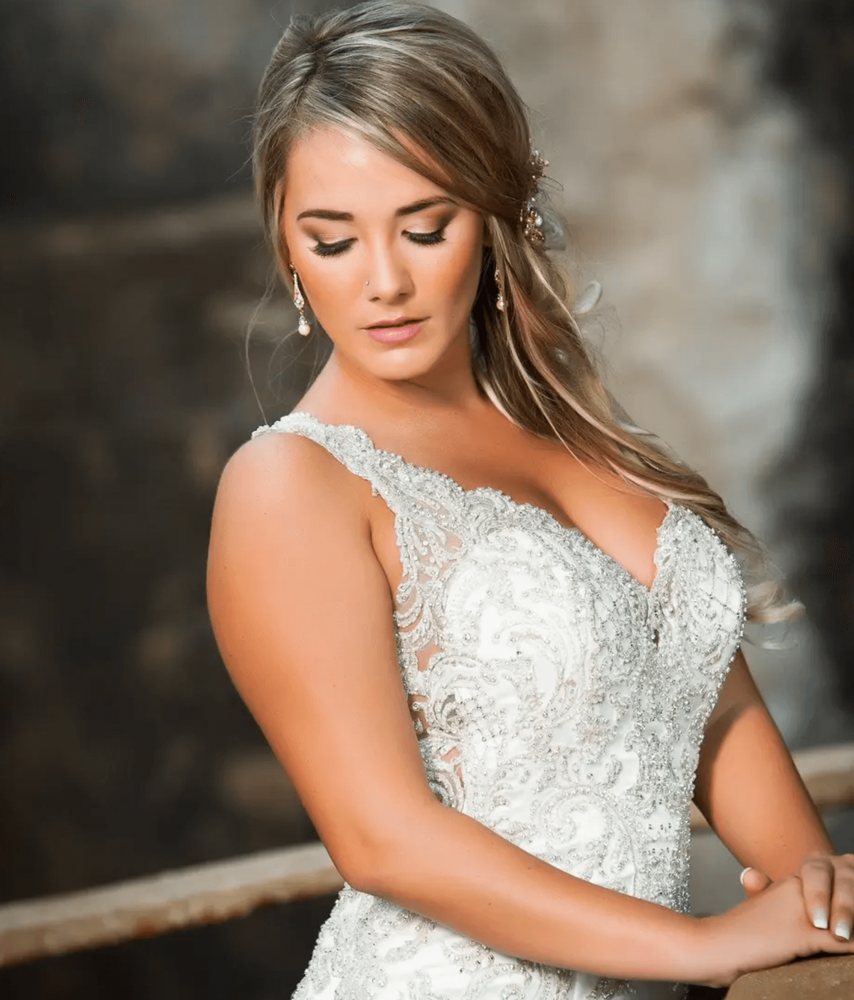 Bride in detailed lace gown with soft side-swept hair and flawless makeup, styled for her wedding day in Dallas by Mistique Makeup