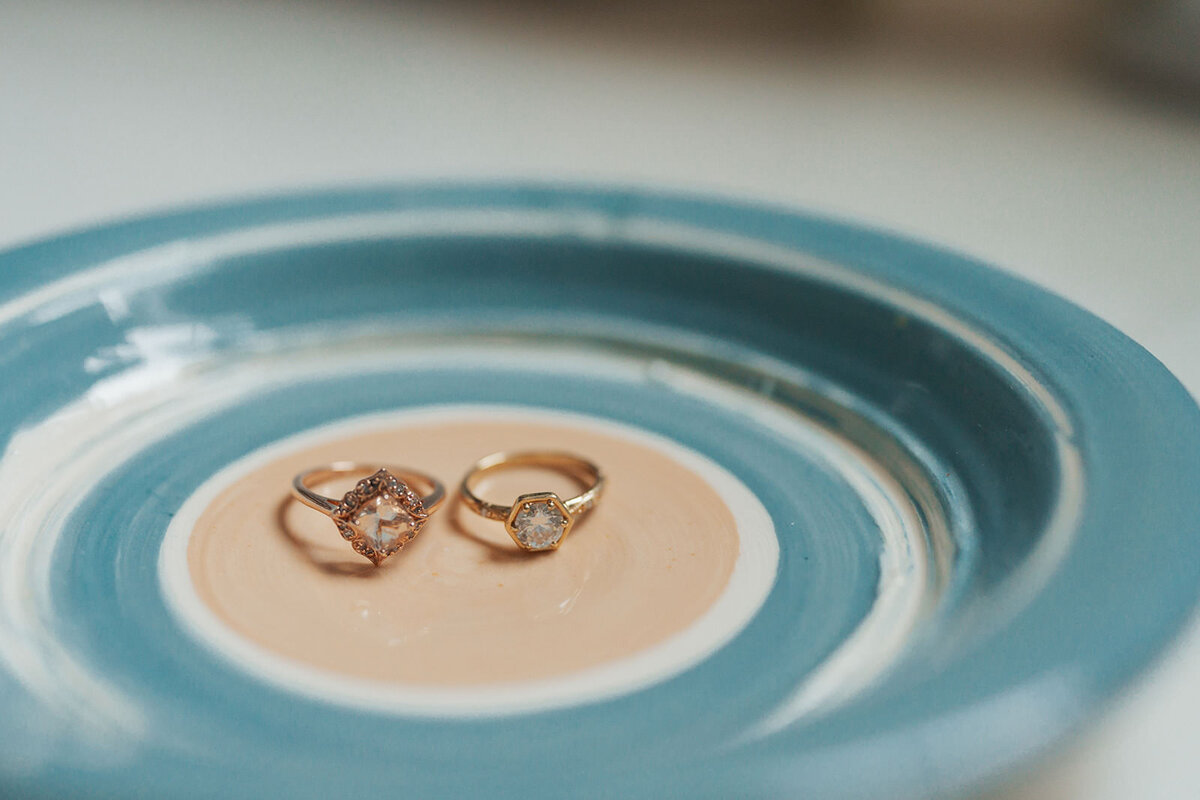 Two wedding rings sit on a glass plate