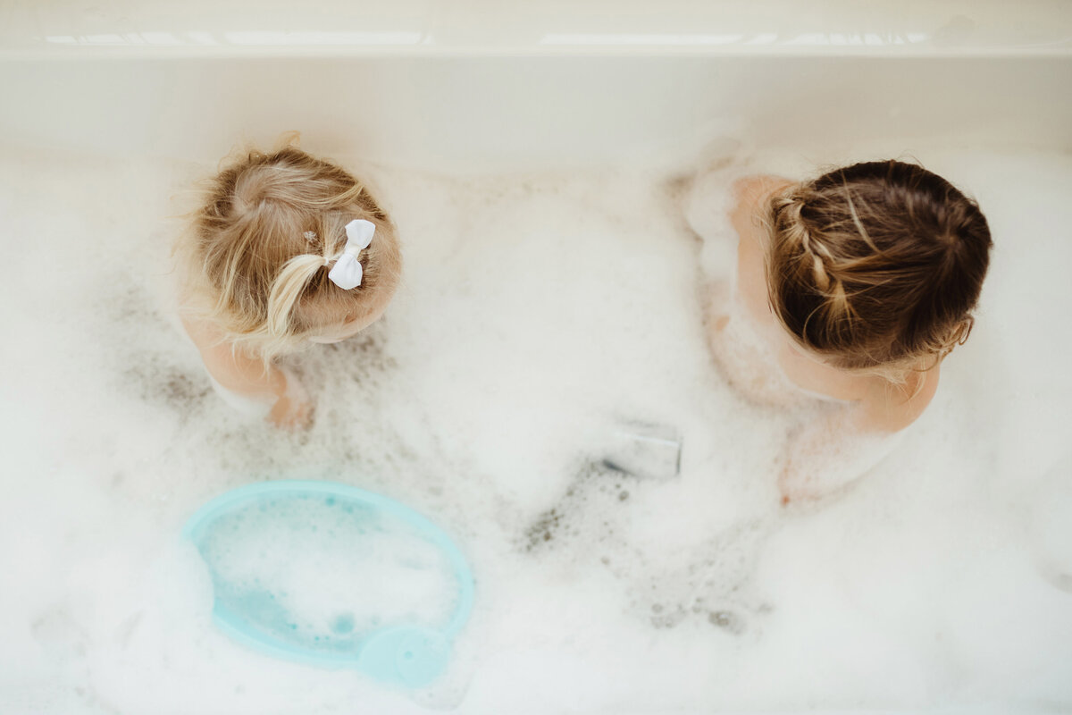 Above-angle shot of two little girls playing in a bubble bath.