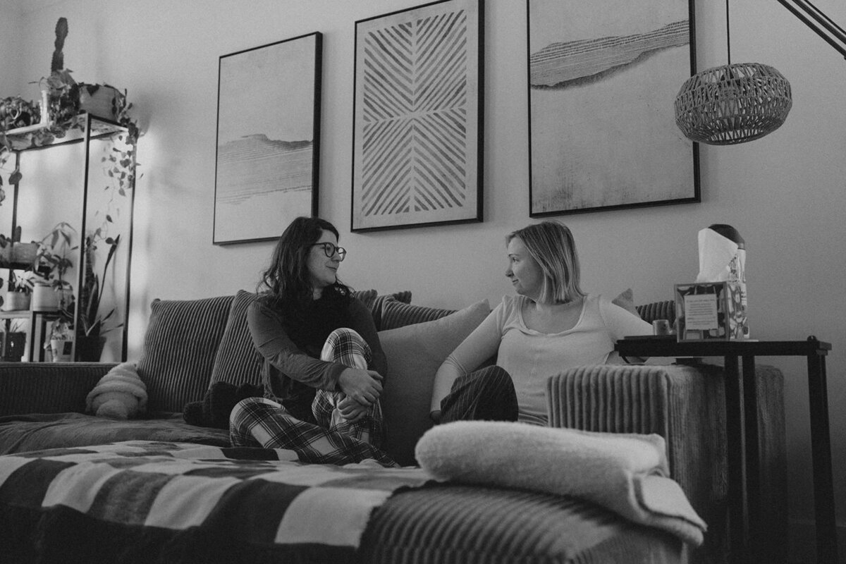 Newlywed women sit on their home sofa with their pet cat
