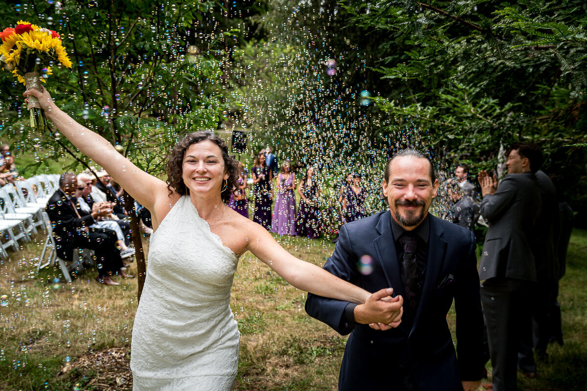 A joyful and whimsical moment as the newlyweds exit their ceremony in Bayfield, surrounded by a cascade of shimmering bubbles and the cheers of their loved ones. A perfect start to their happily ever after.