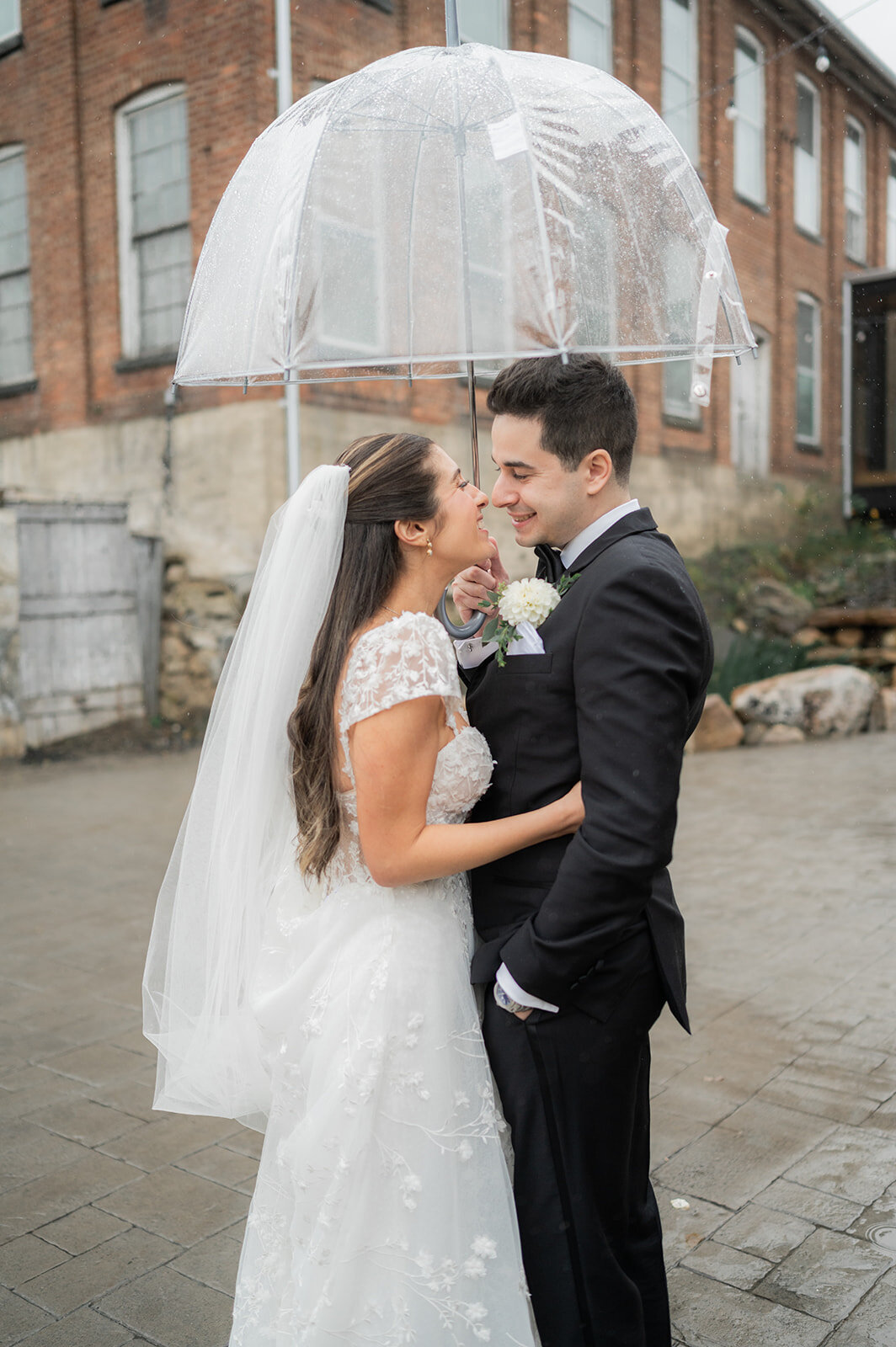 fun moment between bride and groom under umbrella