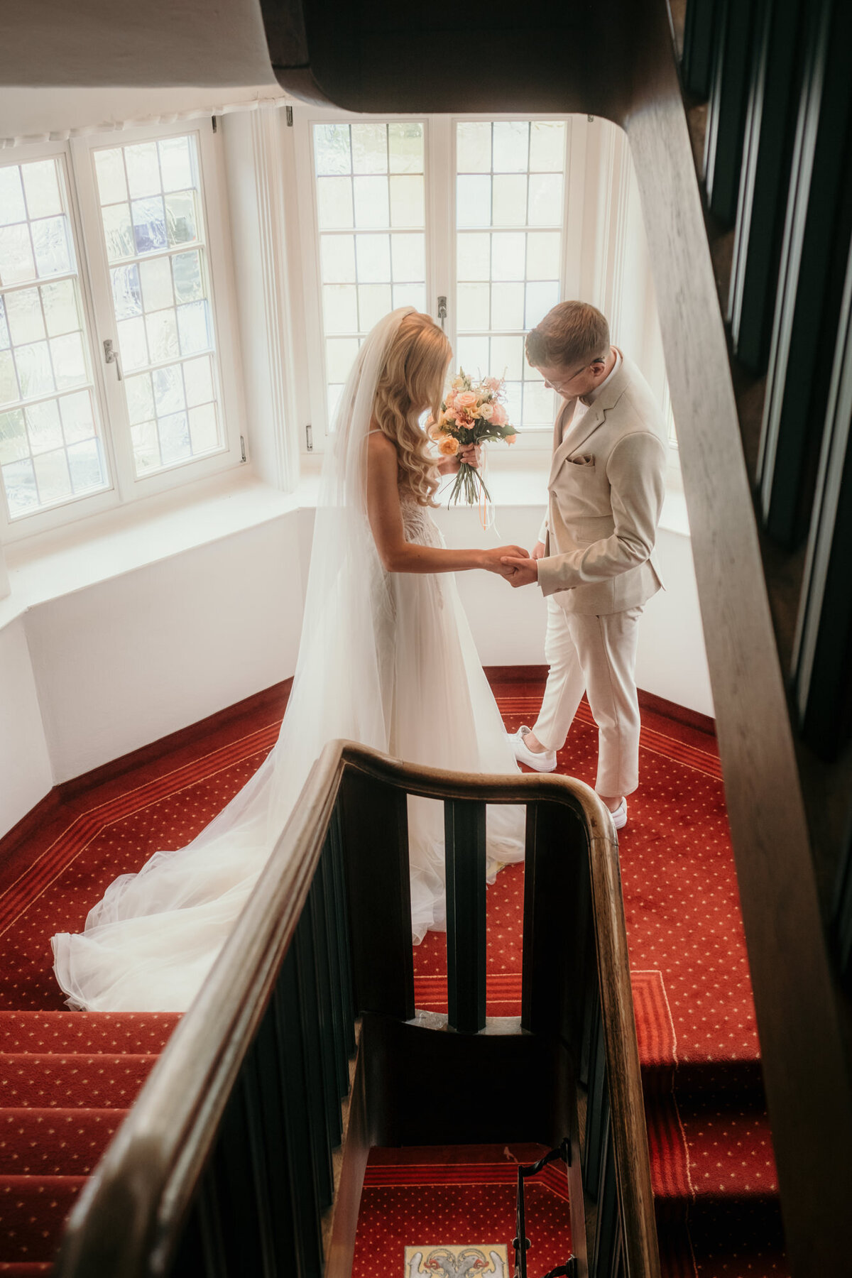 The moment of the first look between bride and groom in a soft lightened staircase with big windows.