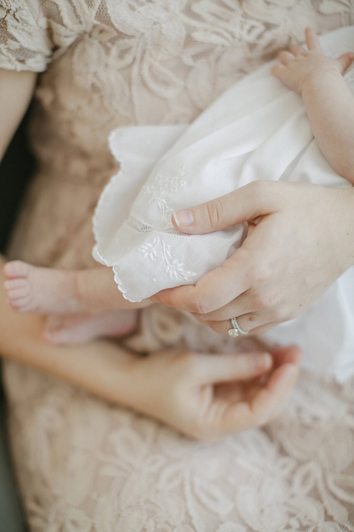 Close up of mother holding newborn in white baptism dress.