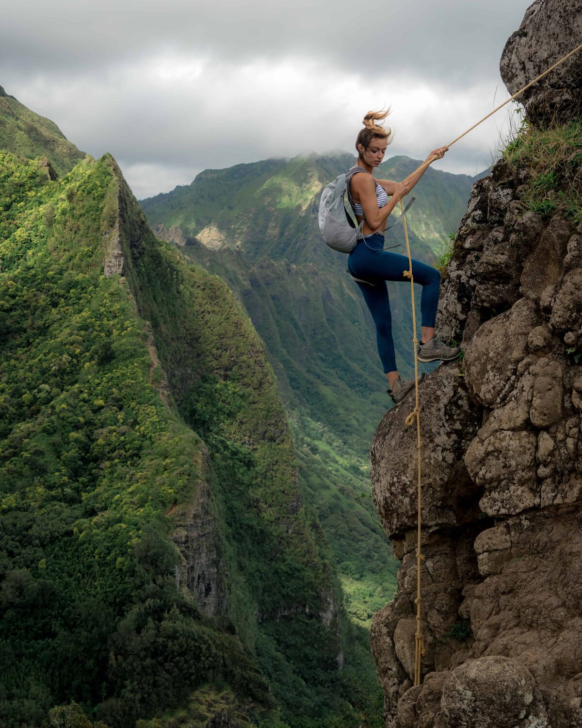 Woman holding a rope climbing up the side of a cliff
