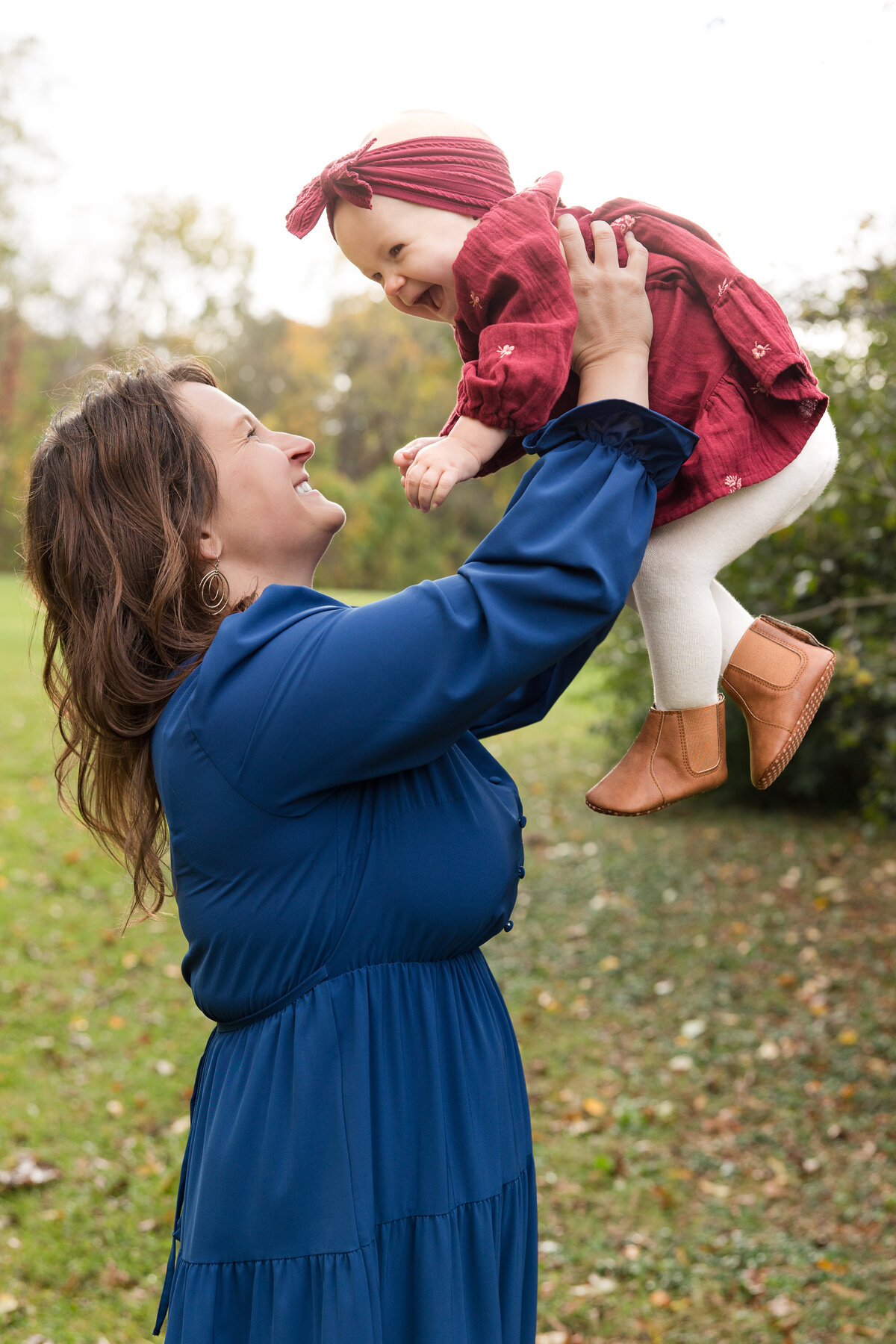 A mom holding her baby girl up in the air and smiling at her