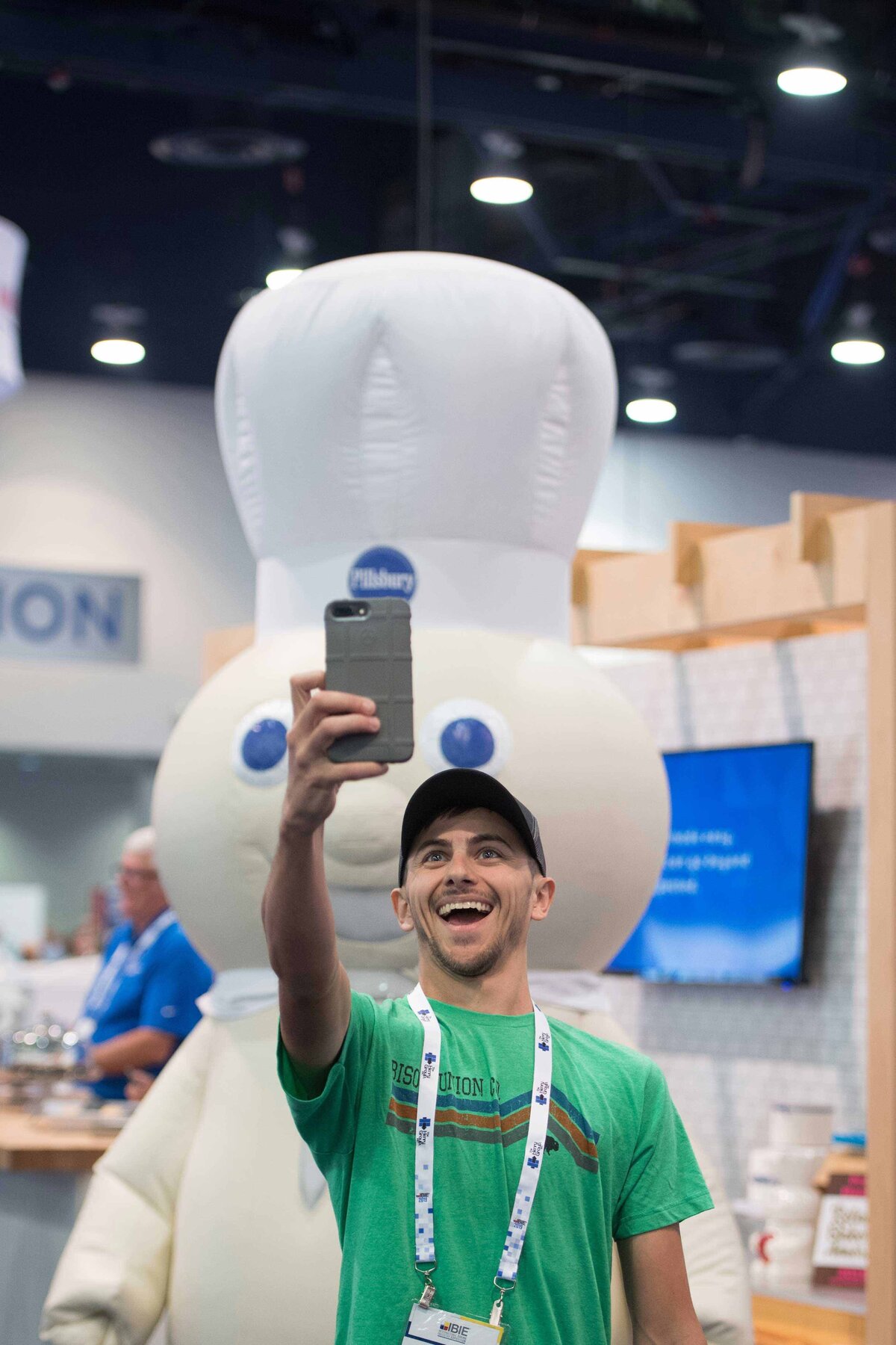 Attendee excitedly takes selfie in front of  Pilsbury Dough Boy  manikin at interesting sales booth