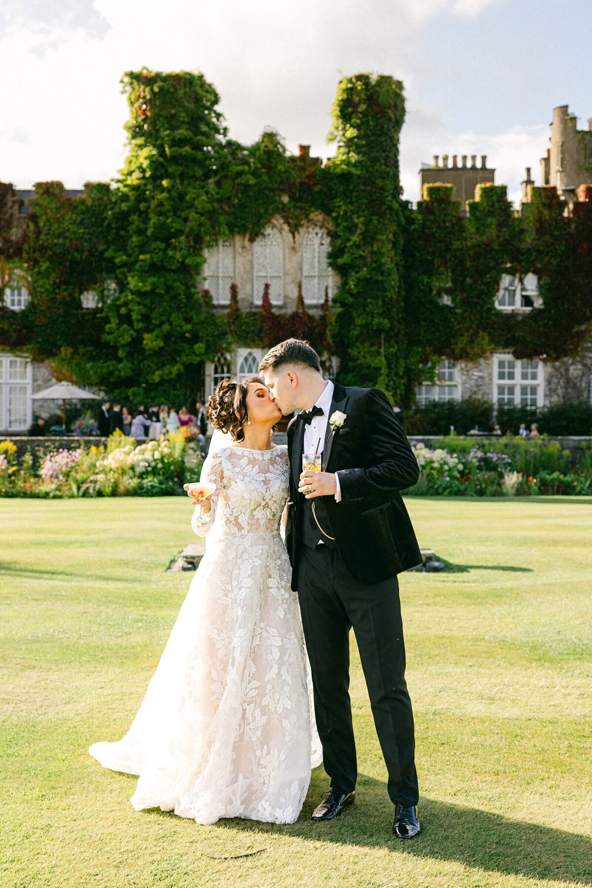A wedding photo of the bride and groom kissing with Luttrellstown Castle behind them