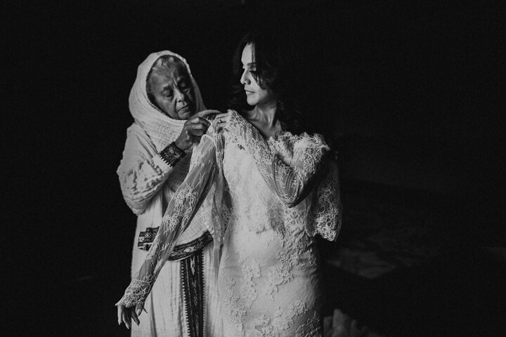 mother helping bride with her wedding dress