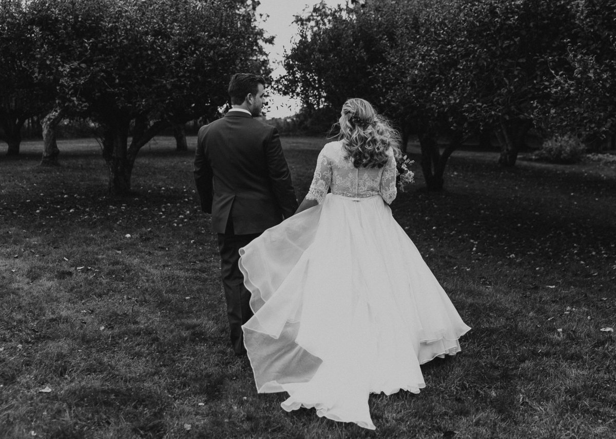 bride and groom walk through apple orchard at John Joseph Inn