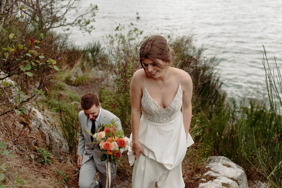 Bride and groom walk back up hill after taking Whistler wedding photos by the lake