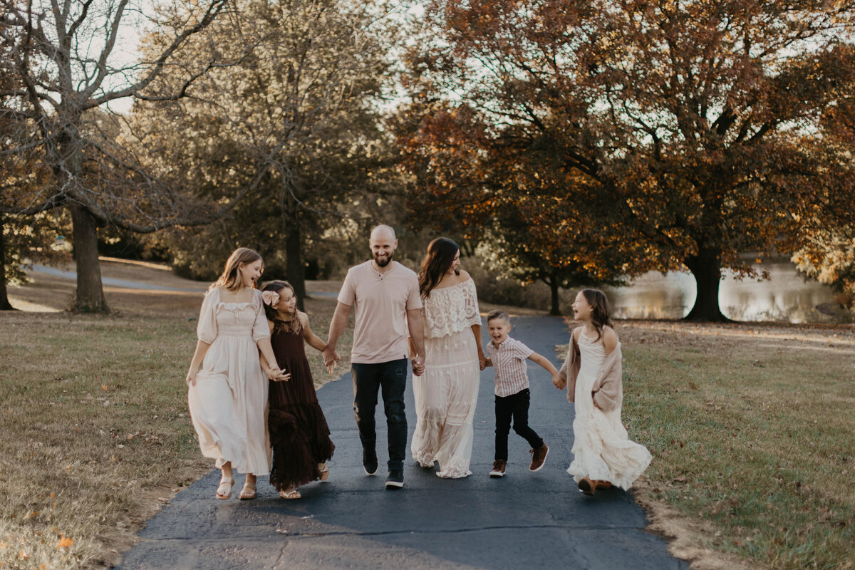 Family of six walking hand-in-hand through a sunlit field.