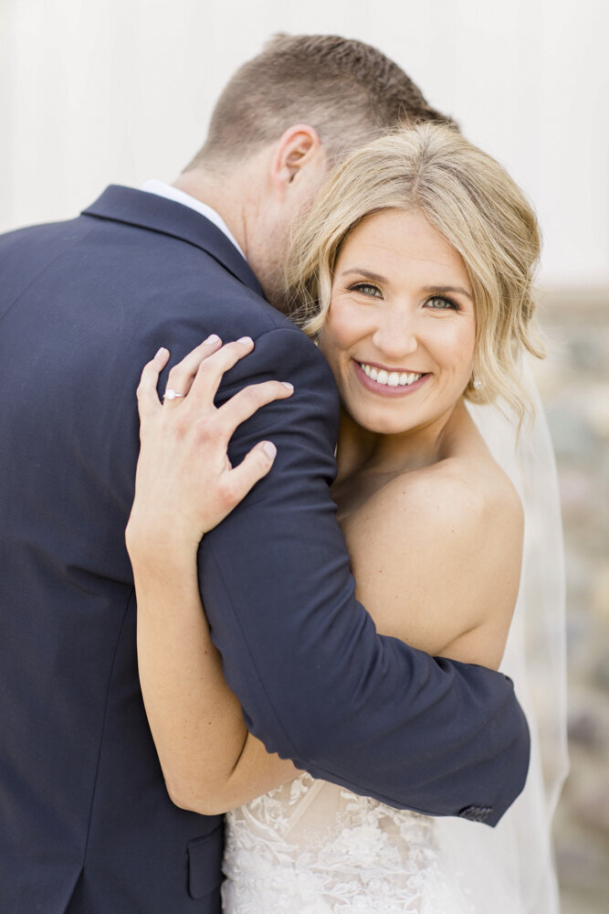 Bride smiling while hugging her groom on wedding day