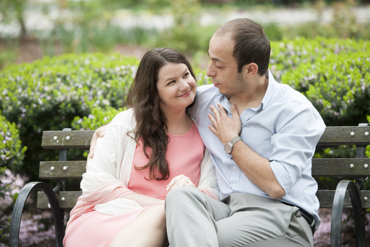 A couple sitting on a bench together talking 