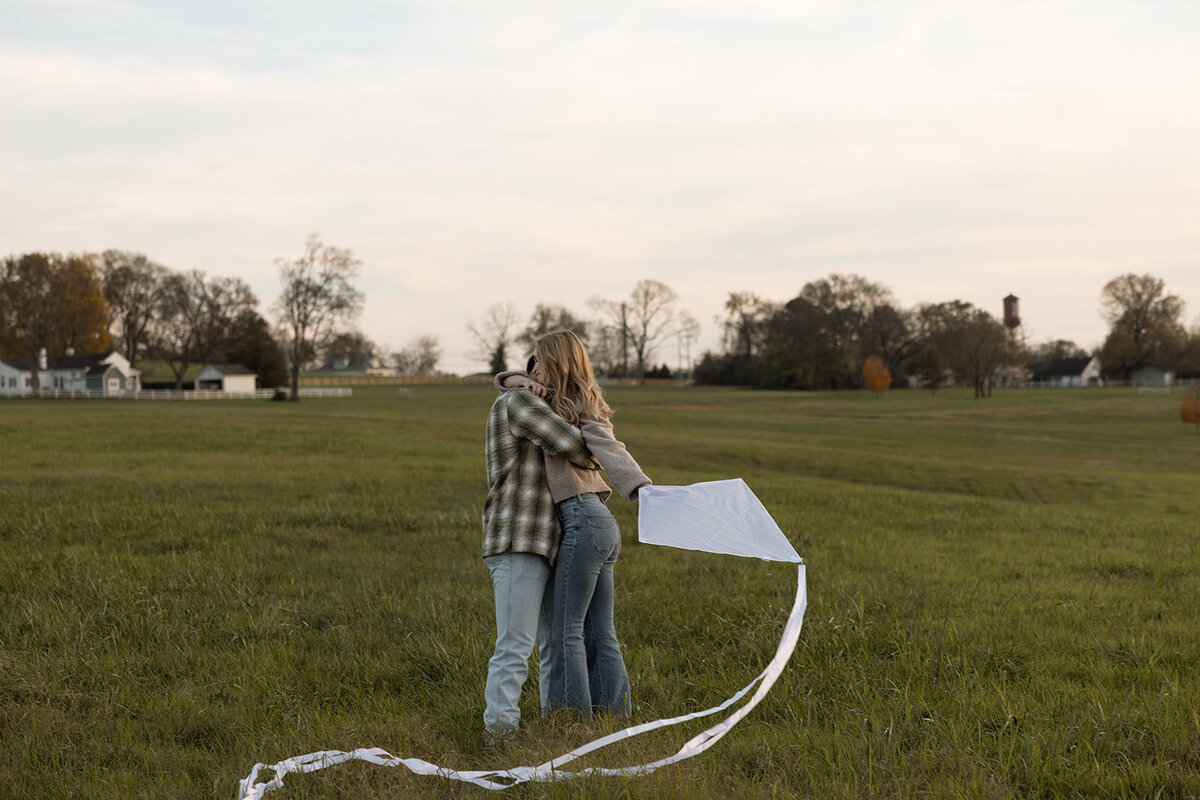 Couple stops for a hug while flying a kite at Harlinsdale Farm in Franklin, TN,