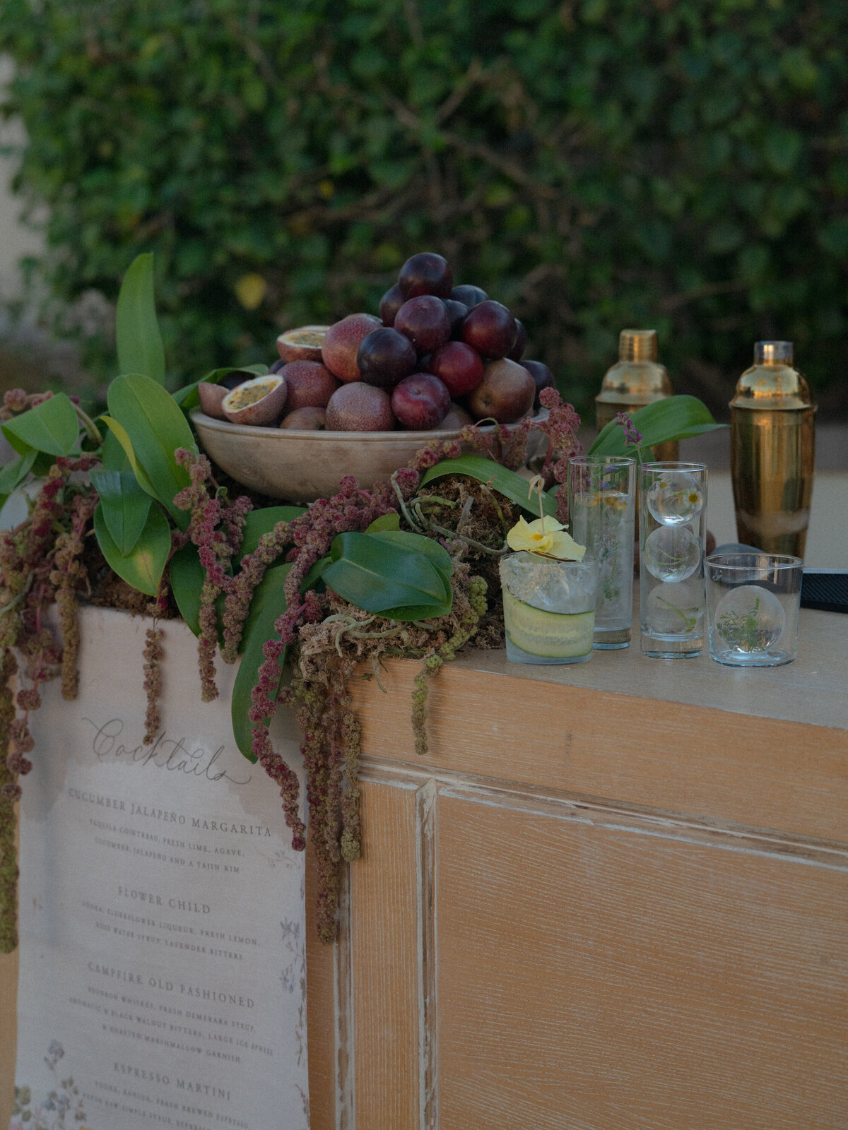 Wedding bar with menu displayed in front,  decorative fruit bowl and cocktails above