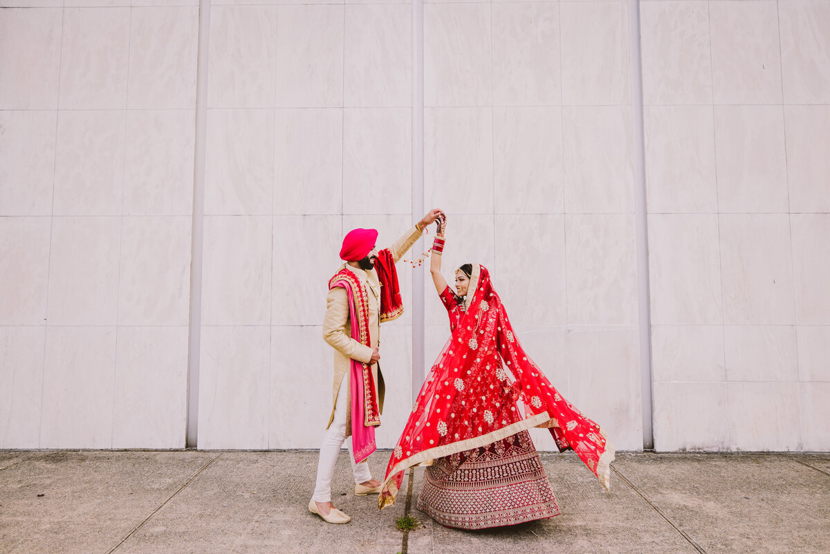 Sikh groom twirling bride outside the Hicksville Guru nanak darbar in hicksville ny on the wedding day