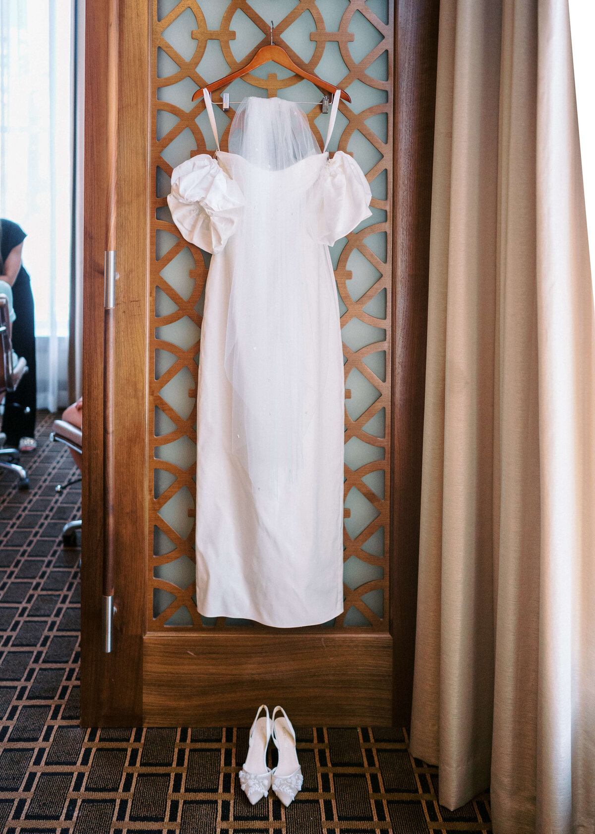 Simple and elegant wedding dress hung up before bride gets dressed on wedding day