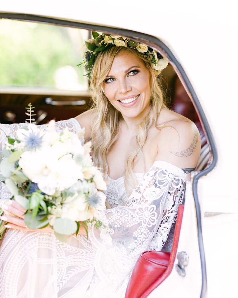 This joyful photograph captures the bride smiling at the groom as she steps out of a Bentley at the River Café on Prince's Island in Calgary, Alberta. The luxurious setting, combined with the bride’s happiness, perfectly reflects the elegance and charm of their luxury wedding day.