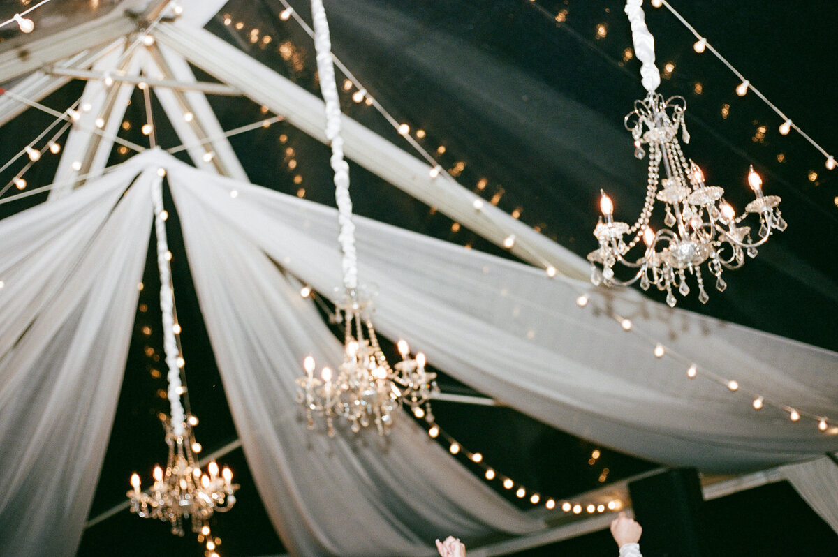 Elegant chandelier detail at an outdoor tent wedding, captured on film in a soft, documentary style — by Kate Winters Photography.