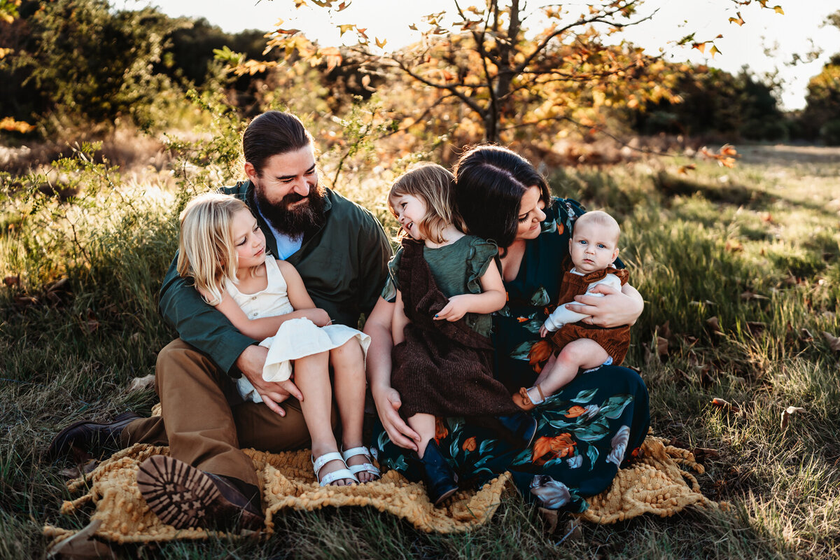 Parents sitting on a blanket with their 3 young children during golden hour in San Diego family photography session.