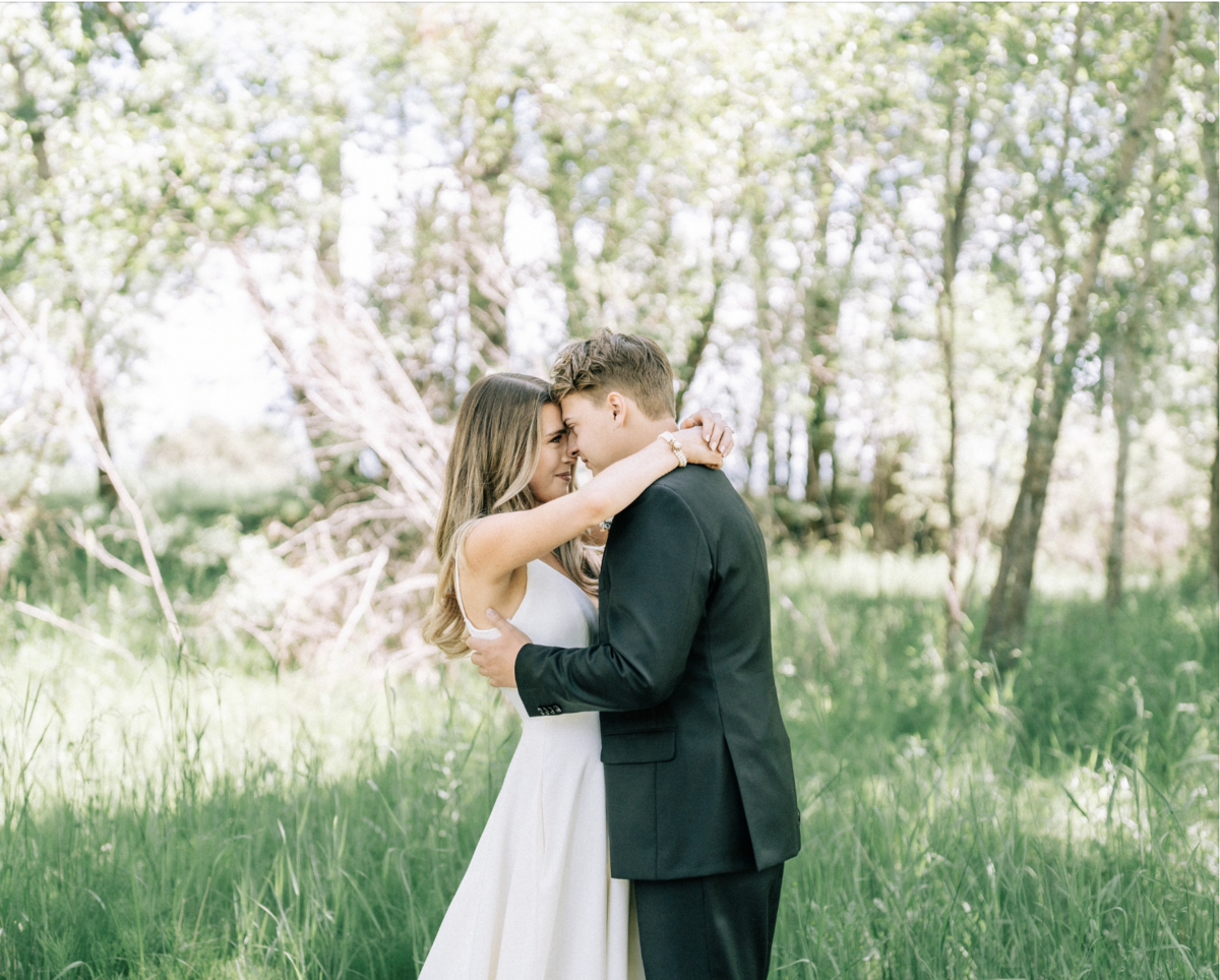 Bride and groom embrace in a grassy field