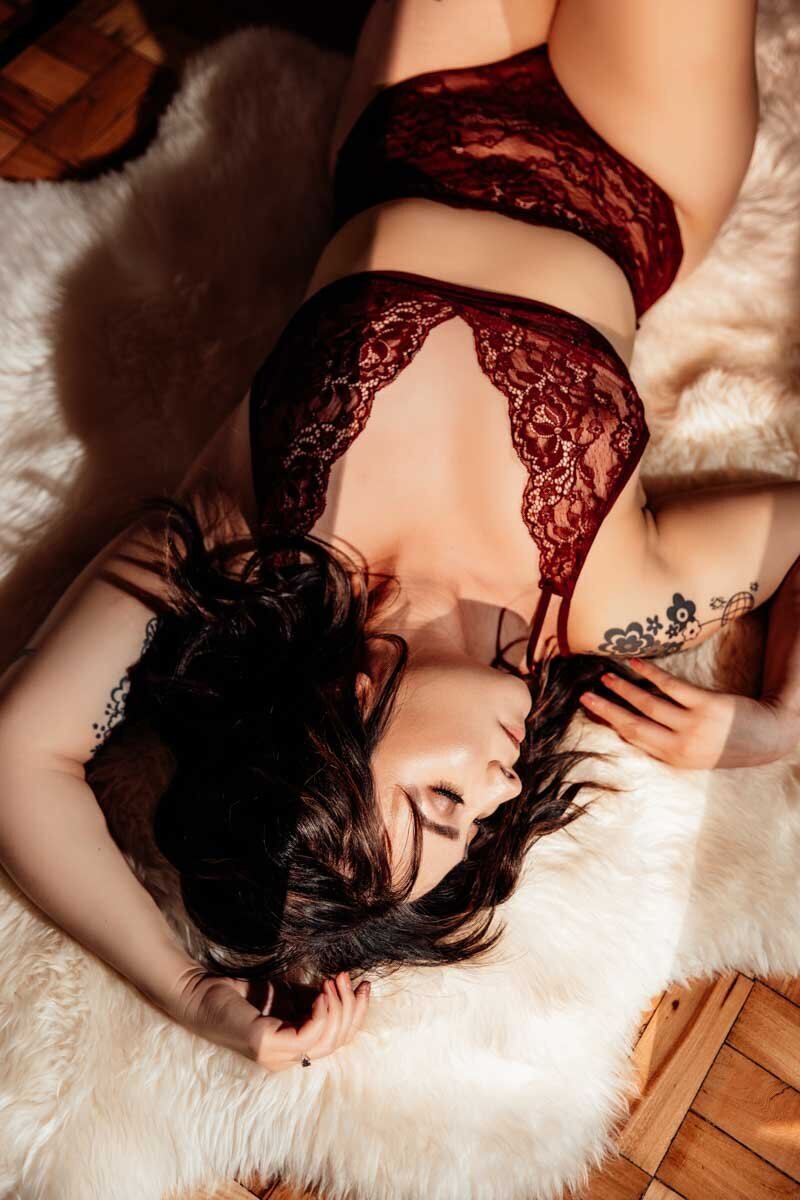 Stunning boudoir photo of woman in maroon lingerie with dramatic lighting