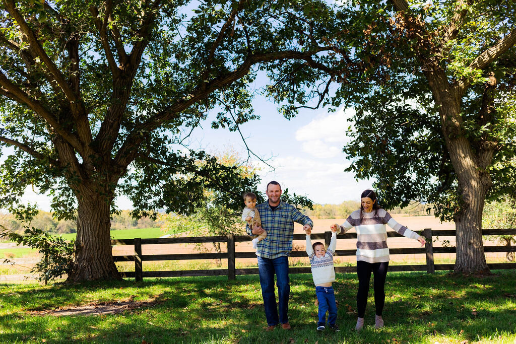 A family holds hands near a fence.