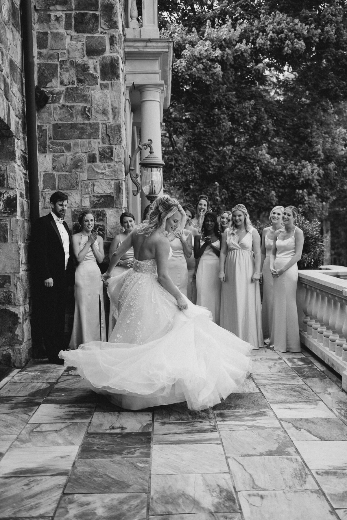 Bride swirling dress in front of bridesmaids