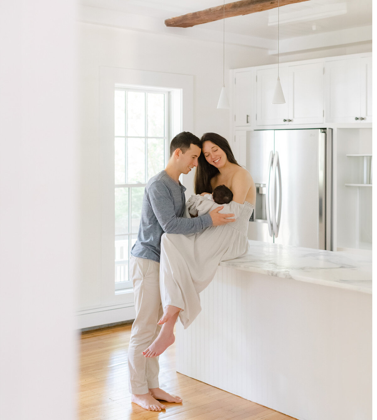 new parents hold baby in kitchen during newborn photo session in boston