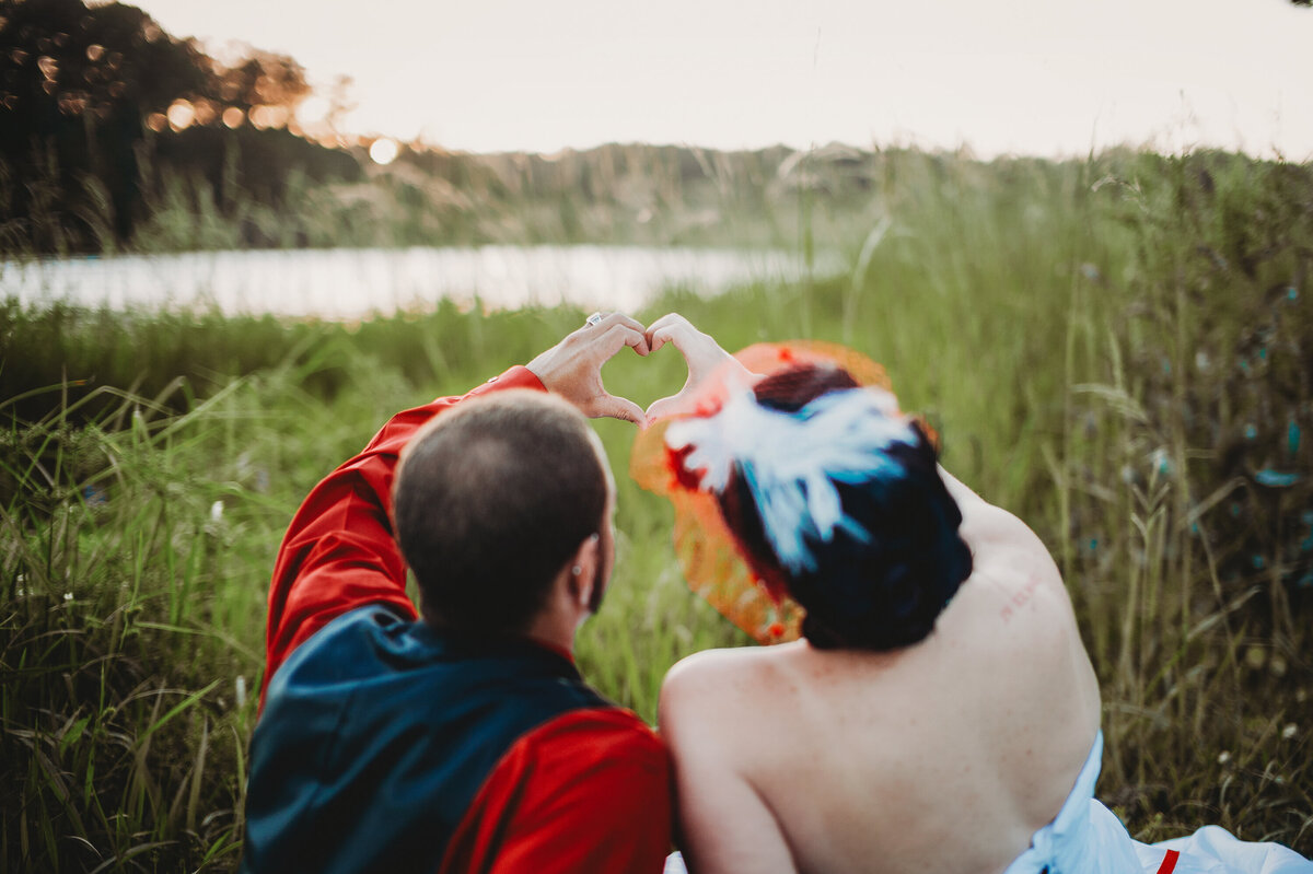 Wedding photo of a couple forming a heart with their hands in an Orlando field.