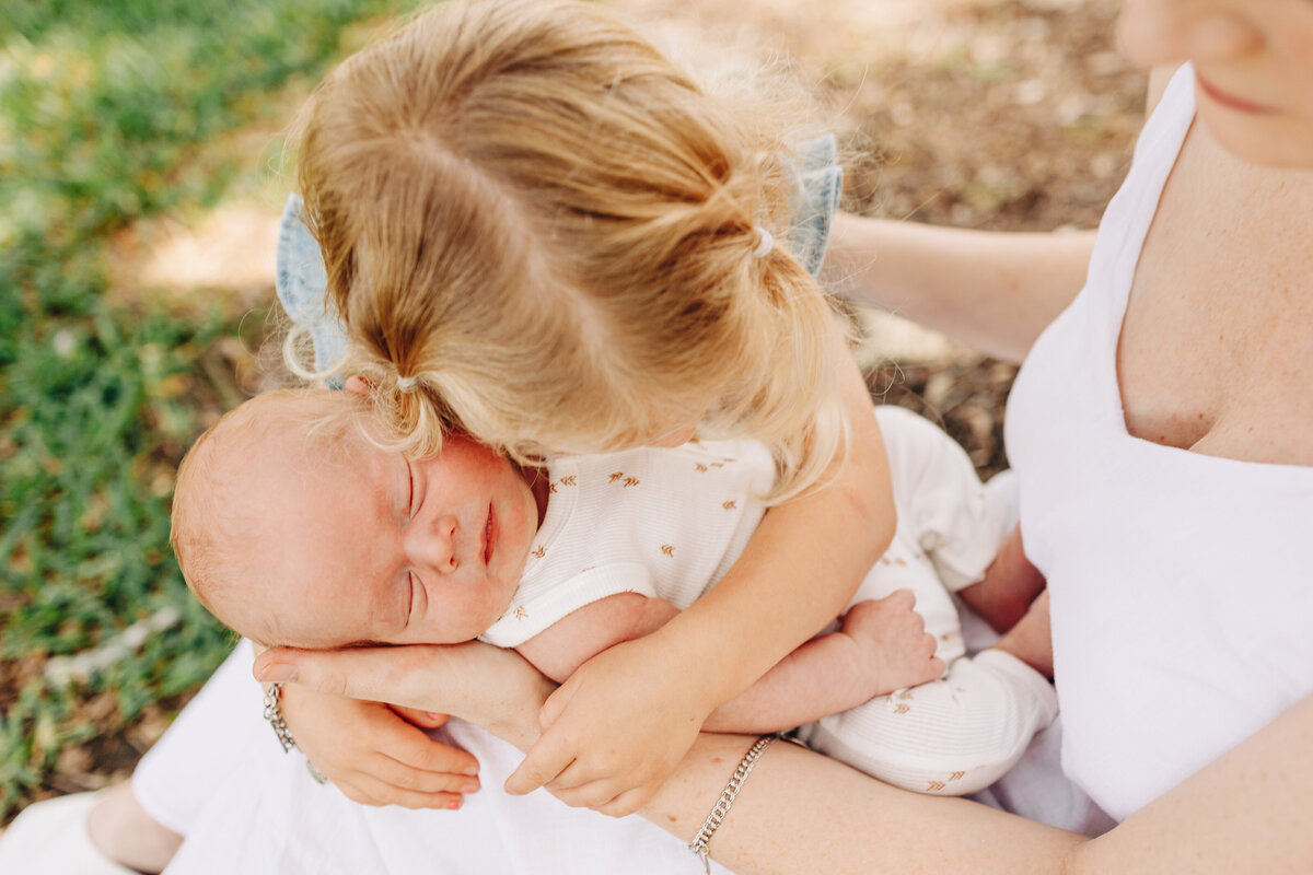 little girl hugging her baby brother taken by a Houston newborn photographer