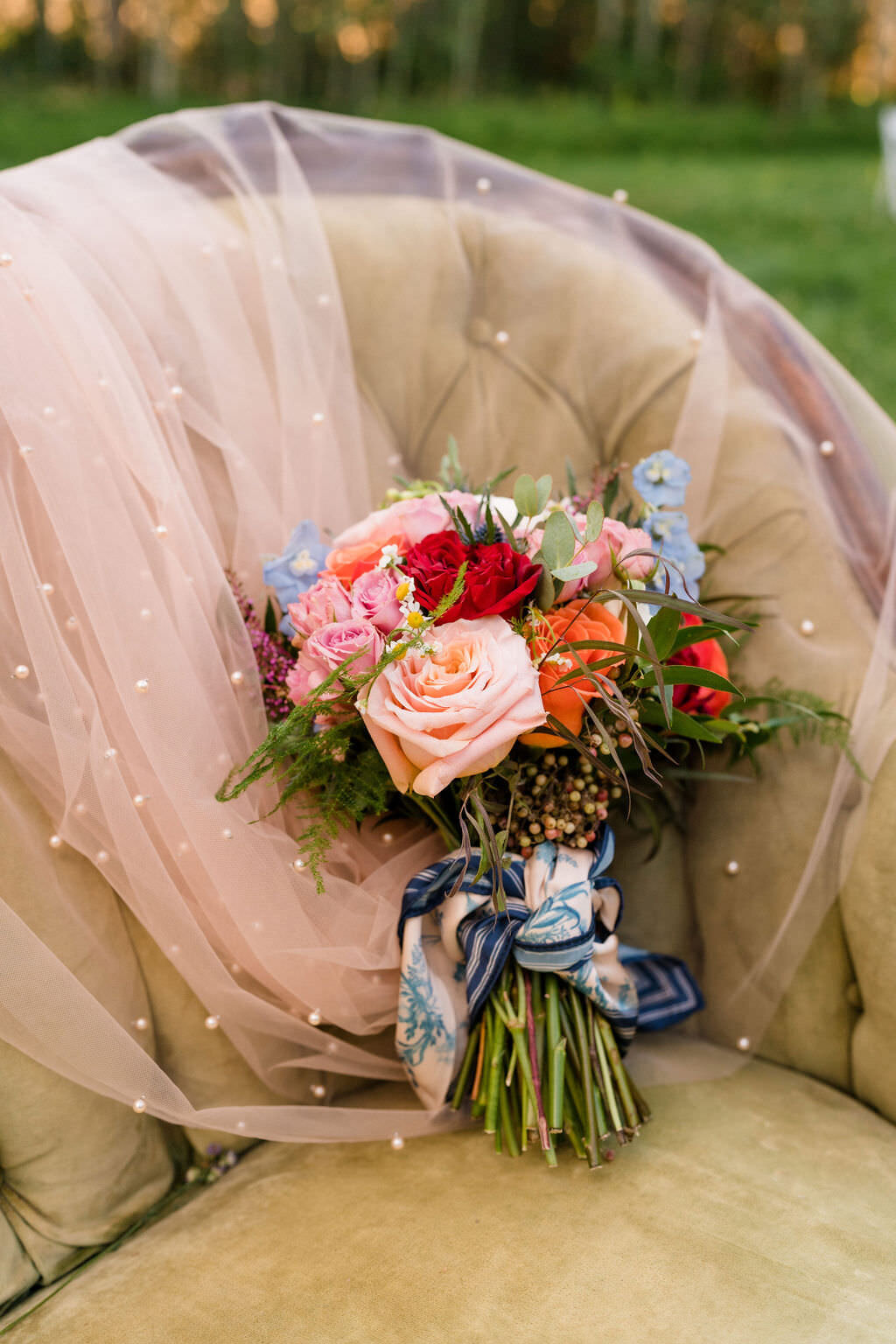pink veil laid over a chair with a colorful bouquet of flowers sitting on it
