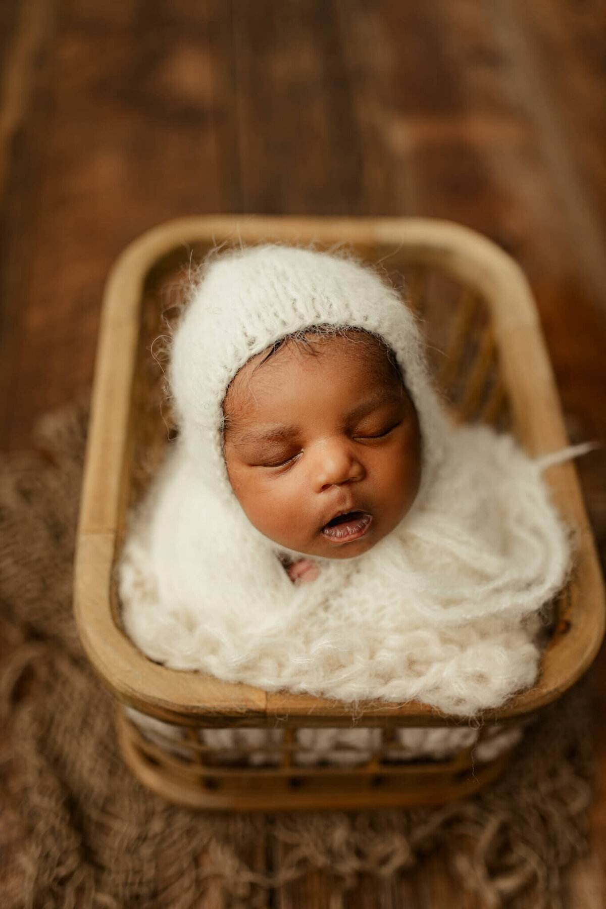 Newborn boy posed swaddled posed in basket