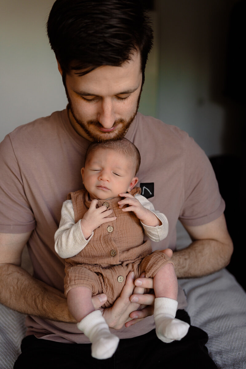 Vader heeft baby voor zich vast net kijkt liefdevol naar zijn zoontje