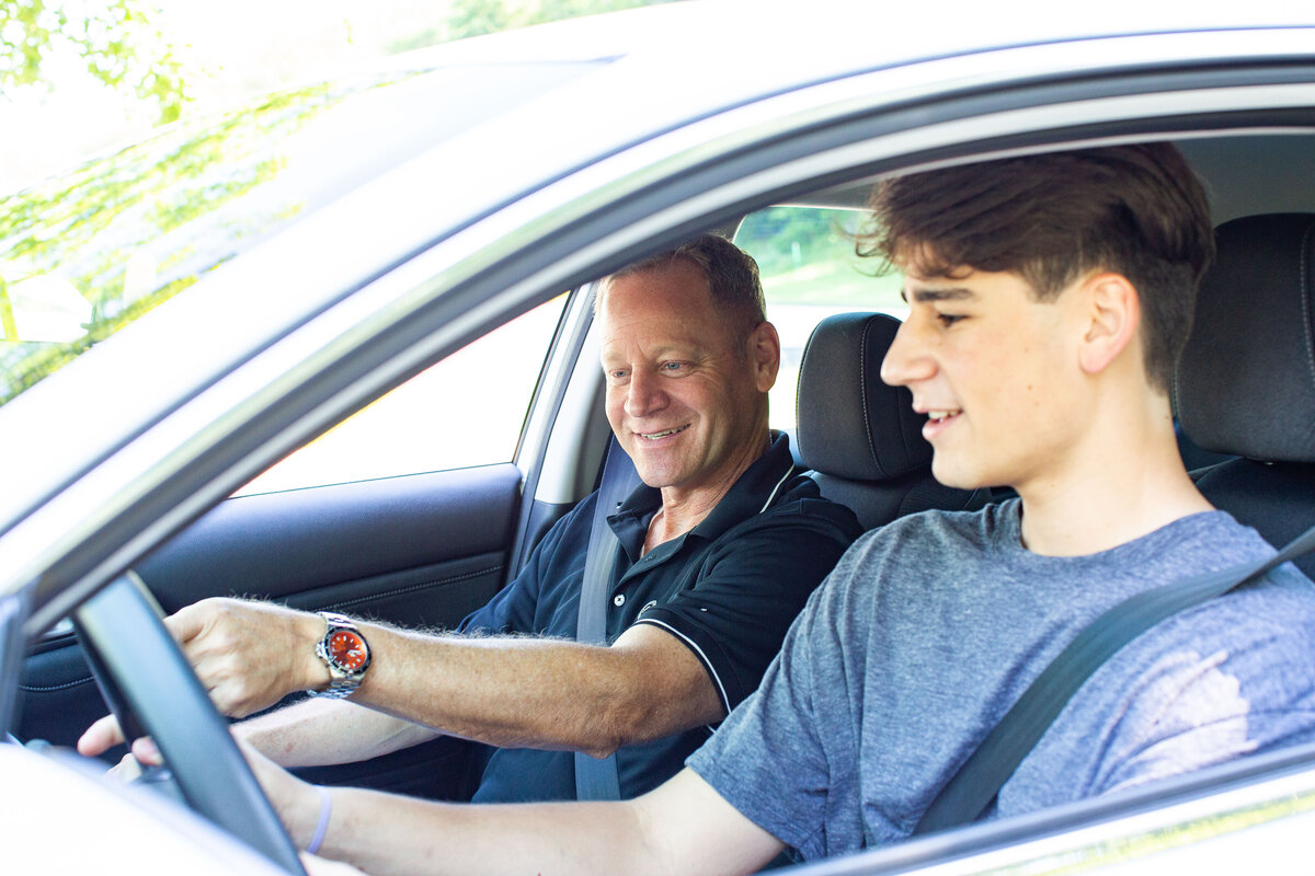 Driving coach in passenger seat, coaching a male student