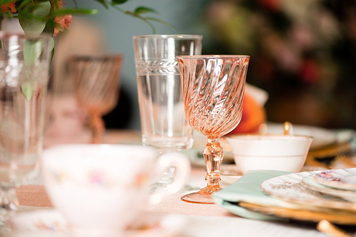vintage glassware at wedding reception at Ravenswood Mansion. A pink glass goblet and a blush colored footed water glass.