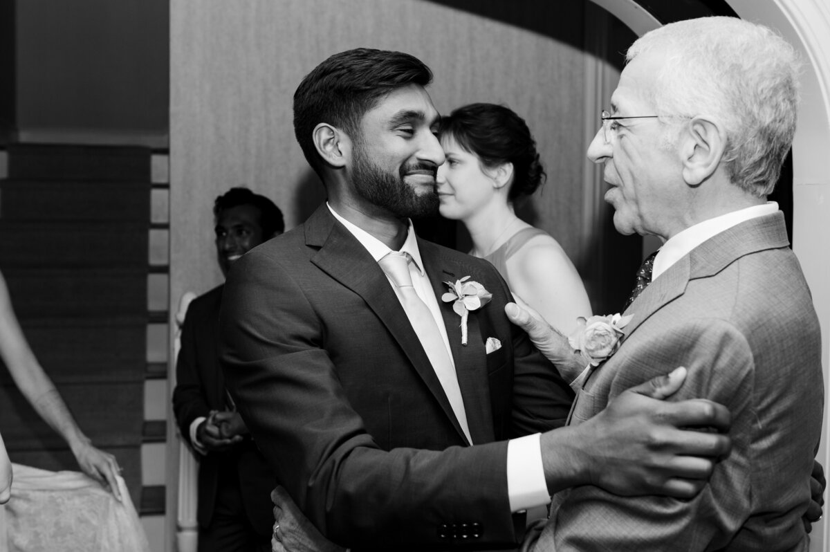 Groom and new father-in-law embrace one another during the wedding celebration in Rocky River, Ohio. Photographed by Aaron Aldhizer