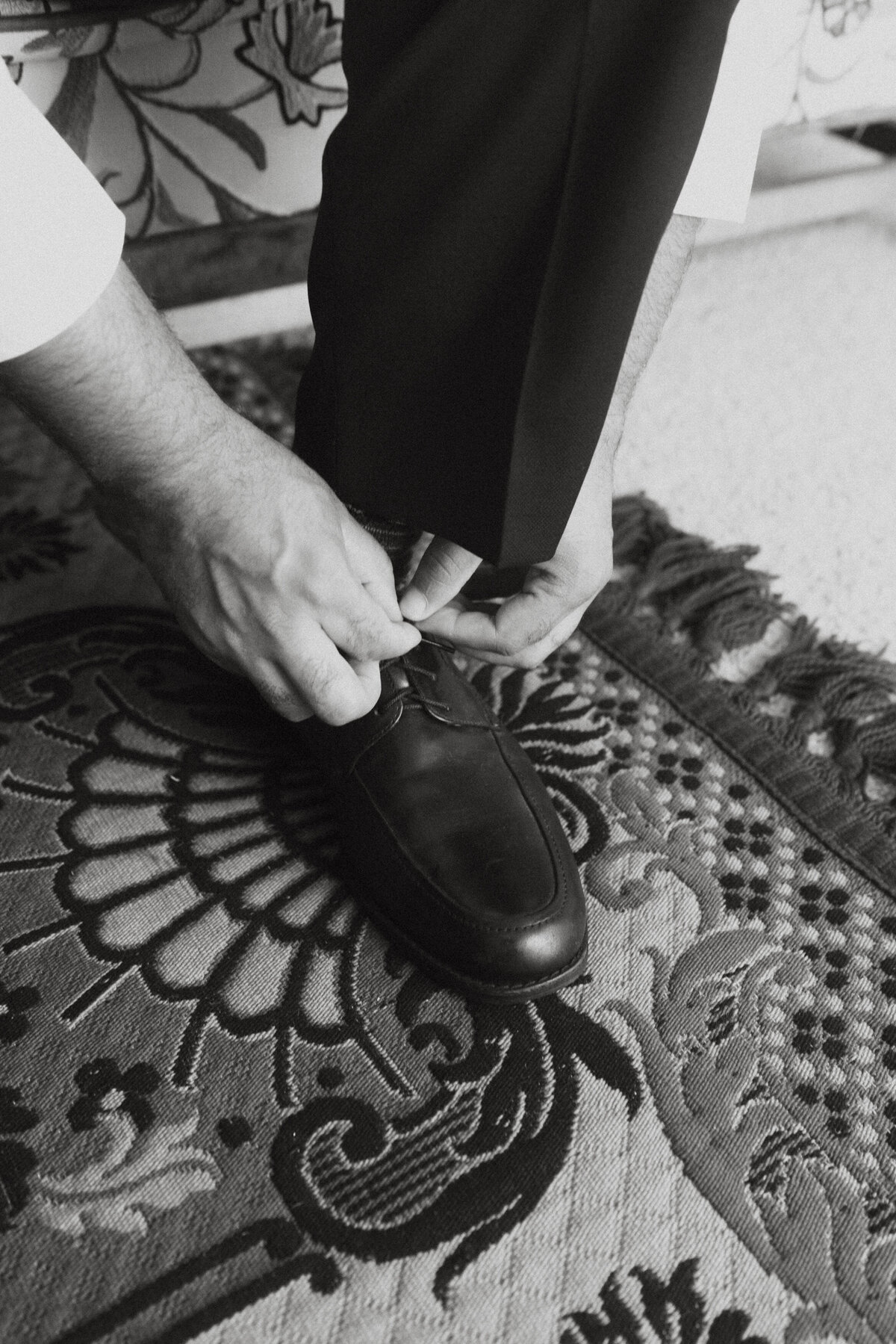 Black and white photo of someone tying their shoes 
