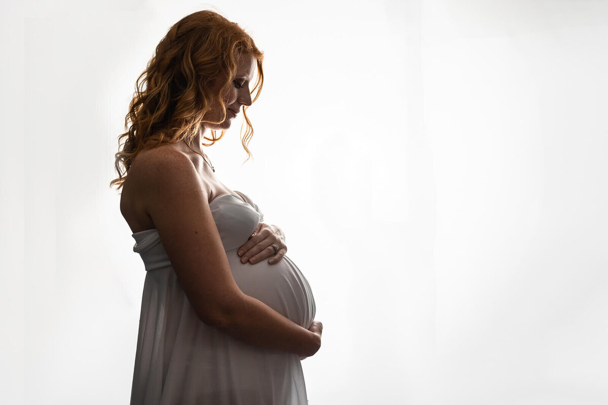 Profile image of an expecting mother wearing a white gown.