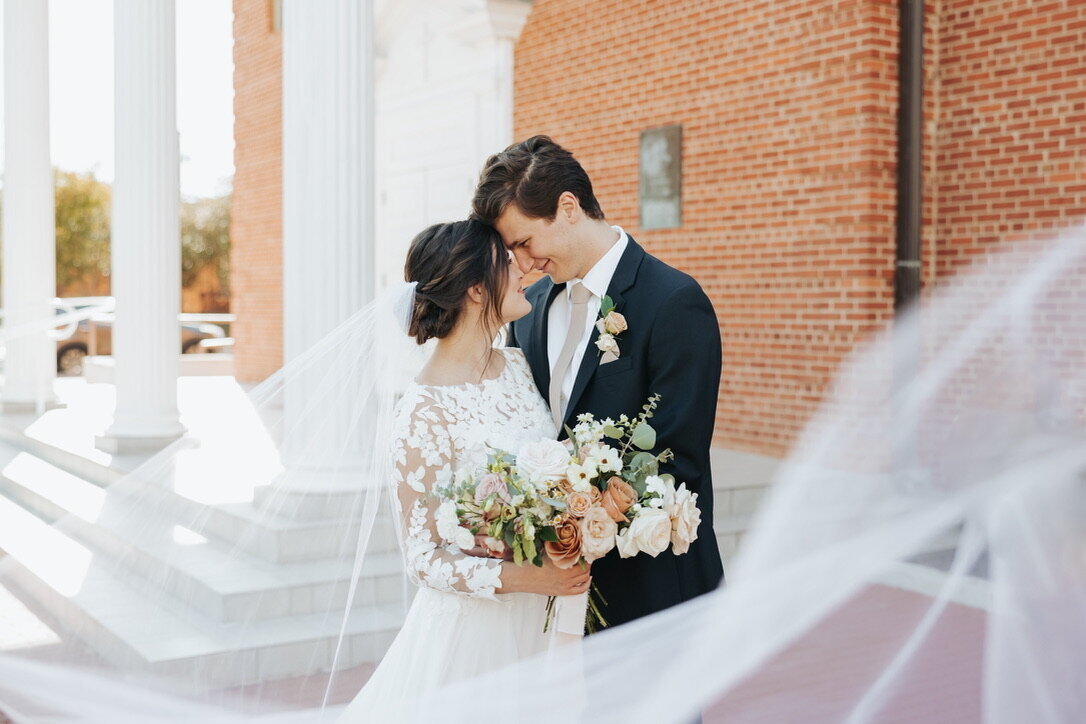 Elegant bride and groom celebrate their wedding while holding bespoke flowers.