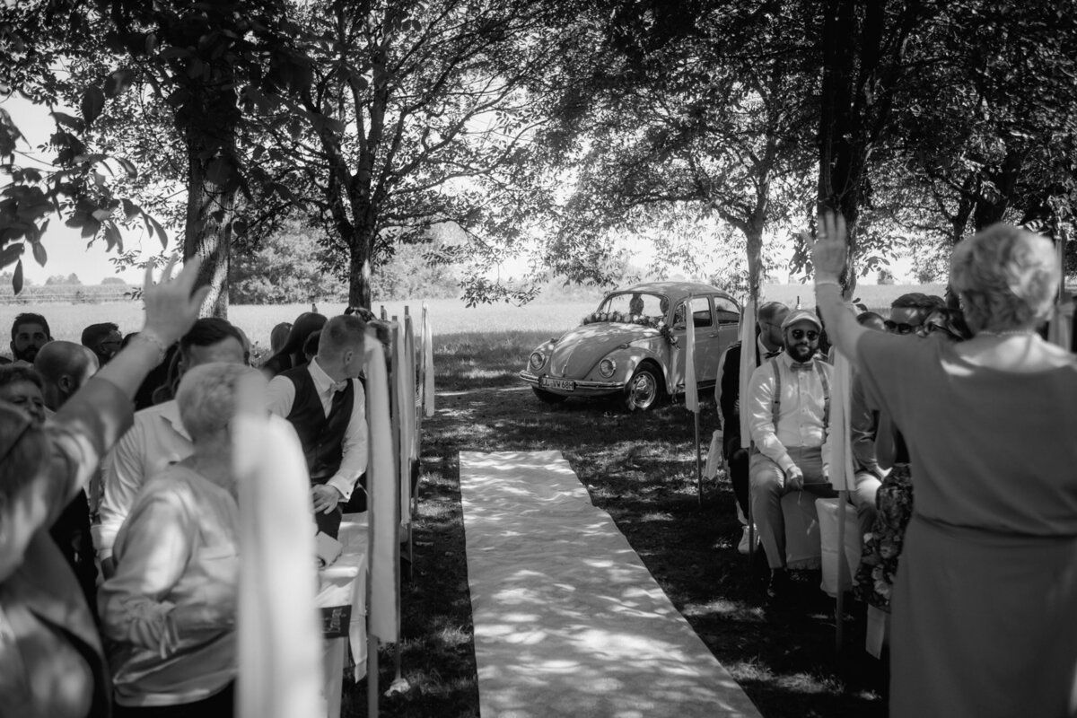 Das Hochzeitspaar fährt bis zum Mittelgang für die Freie Trauung mit ihrem Hochzeitsauto vor.
